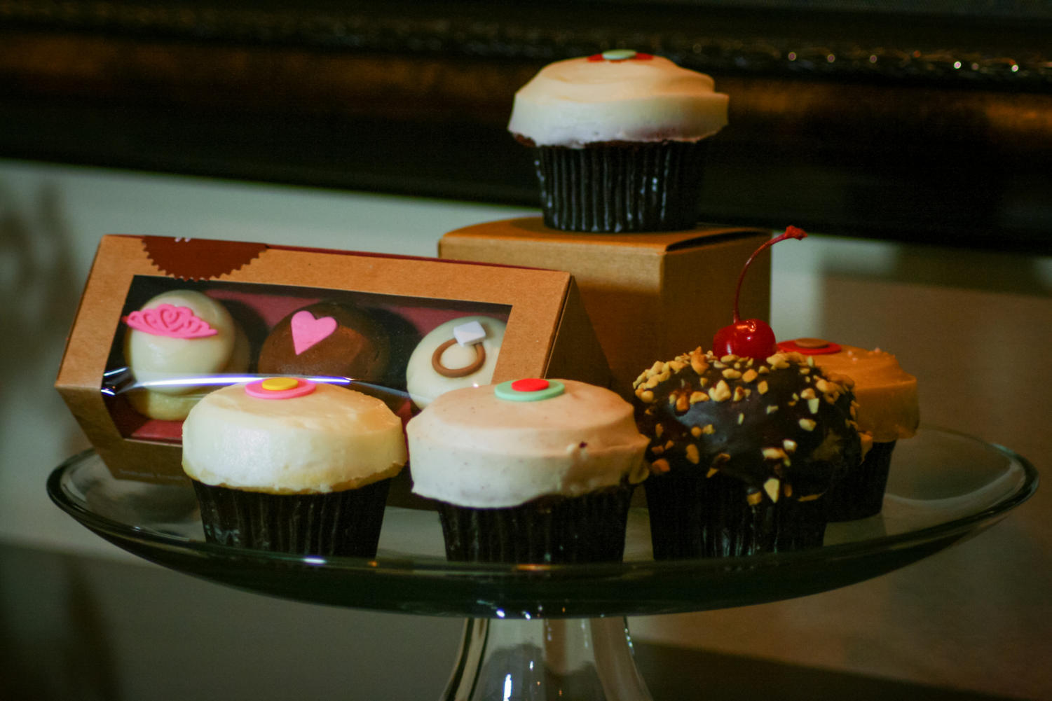 Displayed above from right to left are lemon, carrot, banana dark chocolate and salted caramel cupcakes. The original red velvet cupcake is shown on top.