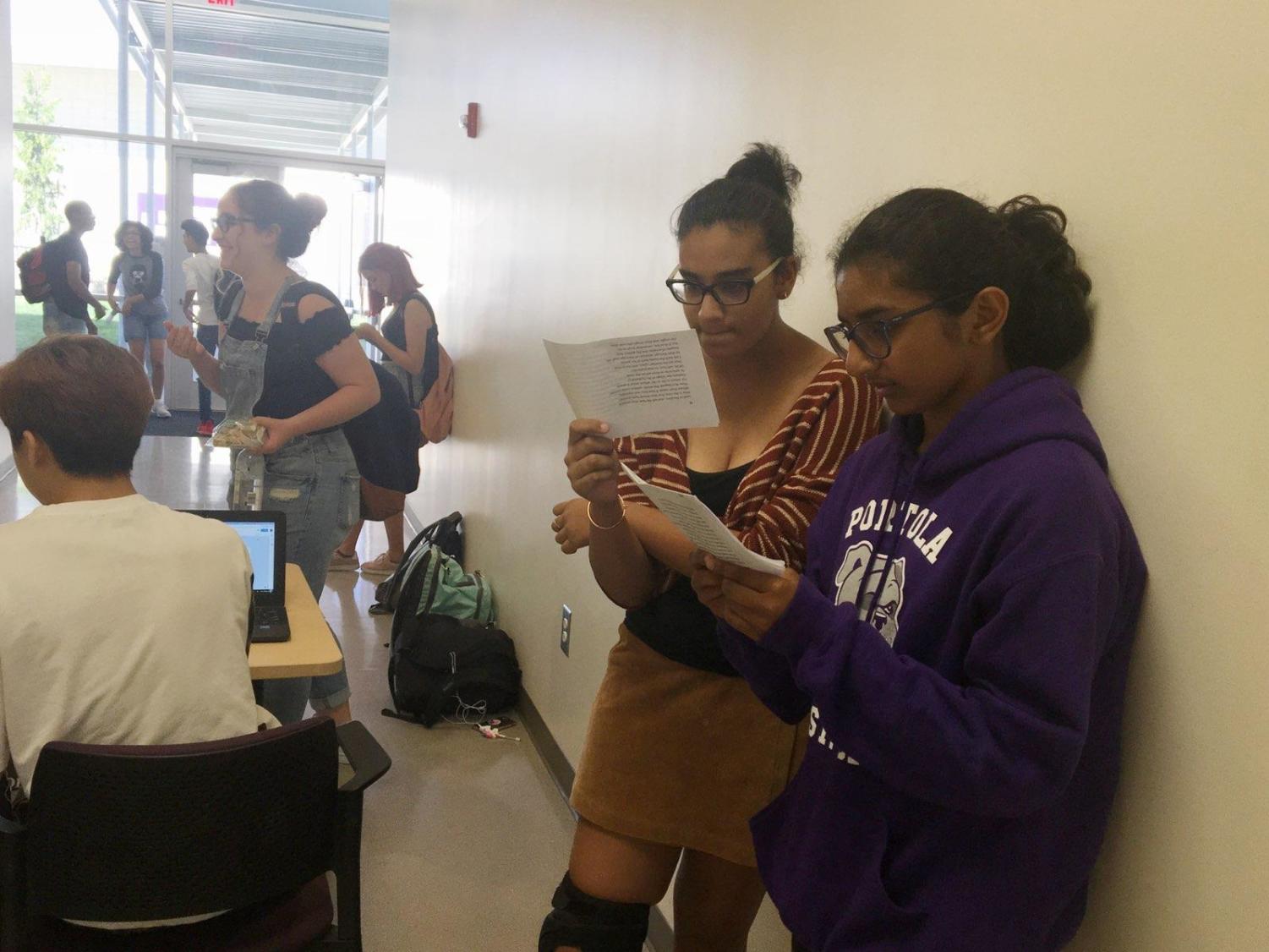 Freshmen Zara Shirwany and Naria Alam intently study their lines outside the theater doors as they wait for their auditions.