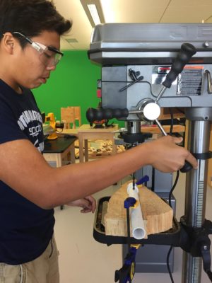 Freshman Nick Hsu makes use of the machinery to drill a hole through a PVC pipe.