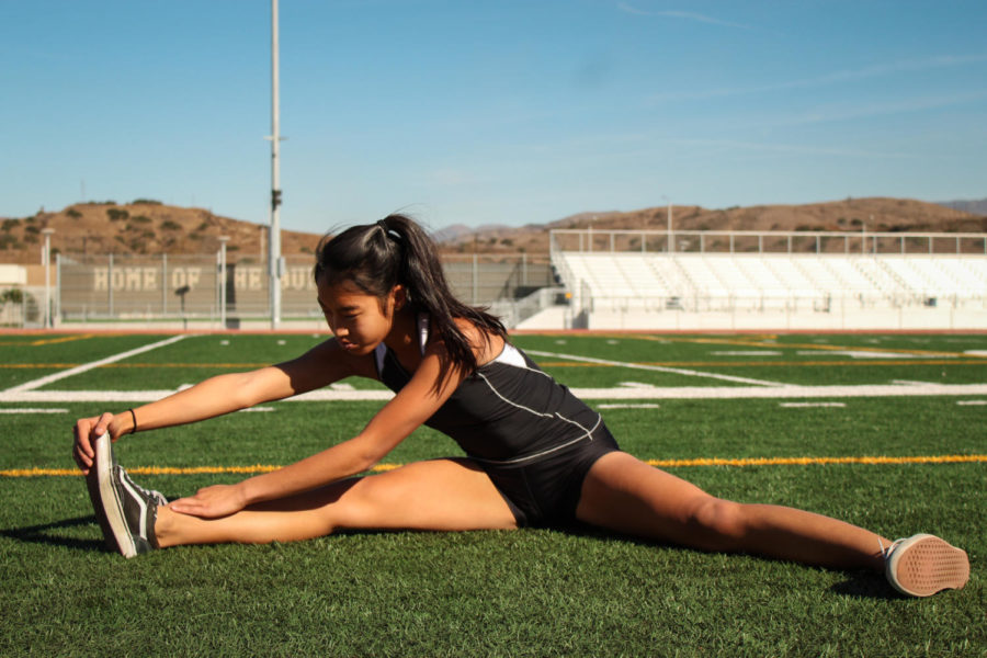 Madison Lam stretches on the field in preparation for her dynamic warm-up and track strides. 