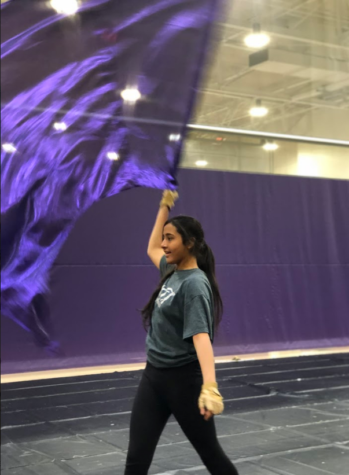 Freshman Mahum Khan flourishes her swing flag to the side before starting her drill during winter guard practice.