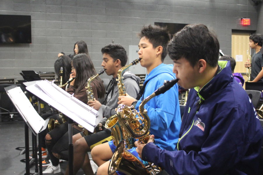 Within the front row of saxophones, alto saxophonists and sophomores Matthew Varughese and Kevin Du and baritone saxophonist freshman Garrett Lee play soulful blues during rehearsal in time with the rhythm and brass sections.
