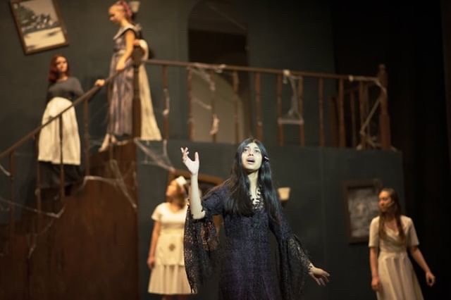 Morticia Addams(Anar Bhatt) sings “Death Is Just Around The Corner” after realizing Wednesday(Rachel Abalos) and Gomez(Nishad Francis) are keeping a secret from her.  