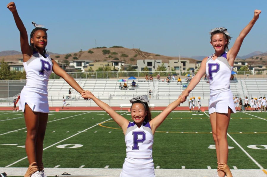 Freshmen side flyers Demetris Owens and Katelyn Toulmin stands next to sophomore center flyer Hailey Kim, in a stunt at a junior varsity football match against Laguna Hills High. 