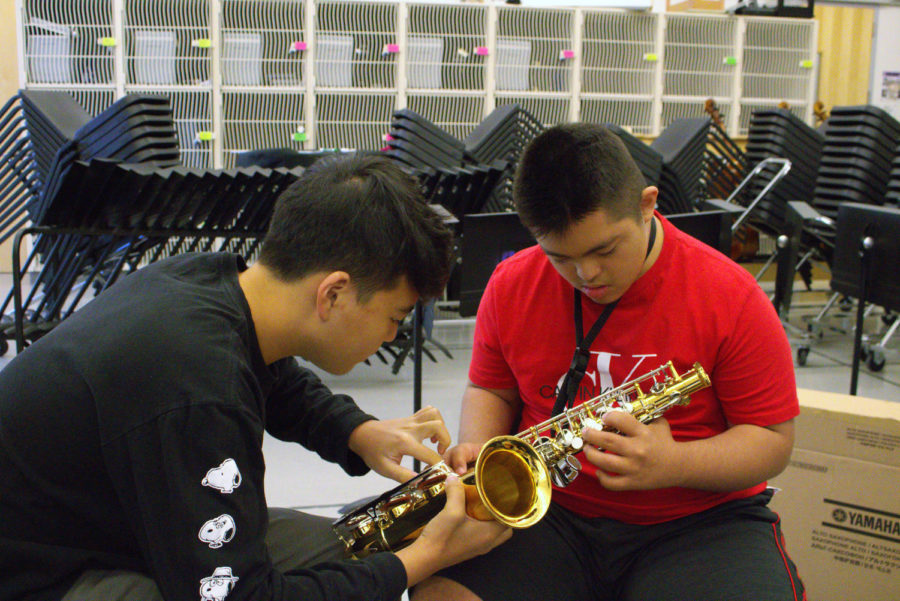 Sophomore and mentor Garrett Lee shows junior and mentee Justin Silva where to place his fingers on the saxophone. For beginner students like Silva, memorizing the location and placement of the many fingerings for the instrument can be difficult, which is why Lee must undergo training in the form of videos and books in order to be able to effectively teach his peers how to play. 