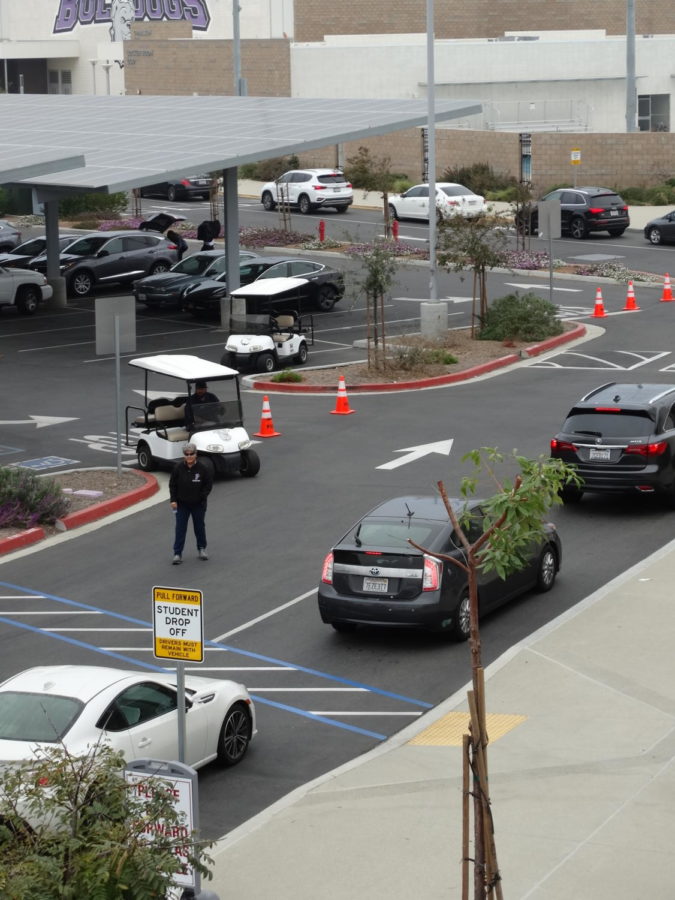 Campus Control Assistants Kathy Elgohary and George Mares supervise the drop-off line to keep a constant flow of traffic. This year, there are more student drivers at Portola High than ever, causing more traffic to build up around campus and on Irvine Blvd. in the morning.