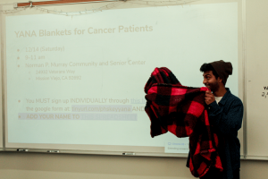 Club technology adviser and junior Ashwin Kunaseelan demonstrates how members will make blankets for cancer patients with other high school Key Clubs at a brand new volunteer event.