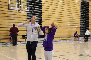 Freshman Molly Lamon-Paredes practices in the gym during her physical education period. Adaptive PE teacher Erie Eastman closely assists students to teach correct form and helps ensure each student enjoys the activity.