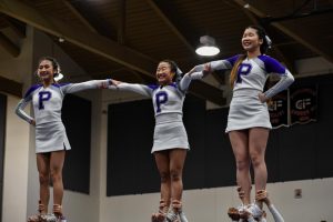 Senior Jessalyn Nguyen, sophomore Hailey Kim and junior Elisa Tan link arms in a stunt at the regional competition. Each cheerleader receives specialized training specific to their role in the routine, and all must work together closely to make the performance possible. 
