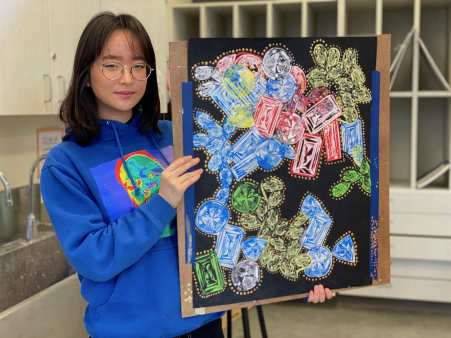 Junior Esther Moon explores the topic of material wealth and its value in society using a printmaking piece with gold acrylic paint embellishments. 