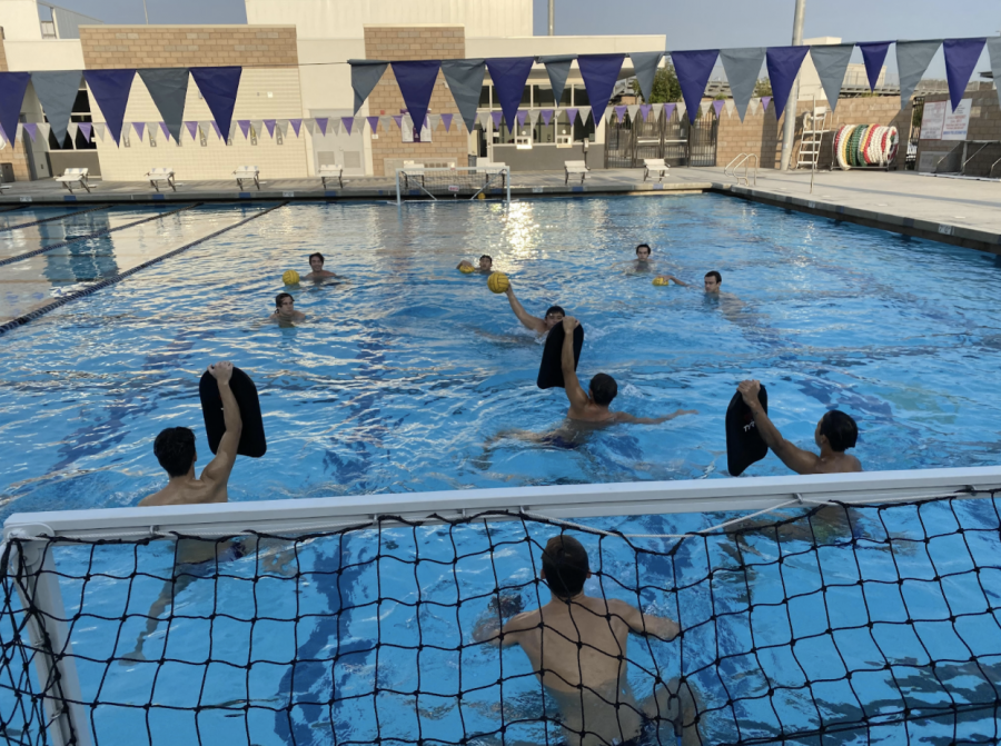 Boys water polo athletes conduct a shooting drill with sanitized kickboards and gloves to minimize contact with the ball.  