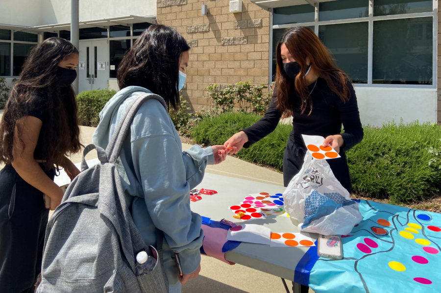 Seniors Sonia Goyal and Chloe Le participate in an activity during break with junior and fine arts coordinator Cinta Adhiningrat. Students put circle stickers on a large design modeled after “Starry Night” by Vincent van Gogh, and as more students put stickers on, the design filled with vibrant colors.