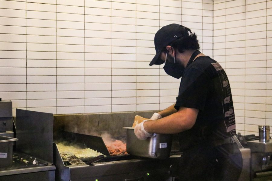 Alumnus and UCSD freshman Farhad Taraporevala lays down meat on the grill, one of the most important roles to ensure that each bowl or burrito has the authentic Chipotle taste. As the most experienced worker of the trio, Taraporevala introduced his former bandmates to work at the Woodbury Town Center Chipotle. 
