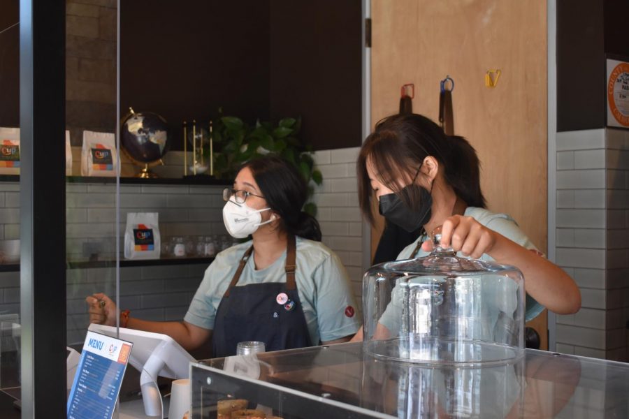Portola High alumna and The Cup employee Anika Garg greets local customers with a smile as fellow employee Chan Hee prepares an order of baked goods on Sept. 18. Most of The Cup’s customers are Novel Park residents and regulars, contributing to the familial atmosphere. 