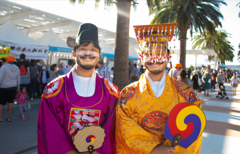 Two men walk around the Great Park, showcasing their traditional Korean attire. Korean traditional clothing for males usually consisted of long robes with wide sleeves and a black hat with two flaps on the side.
