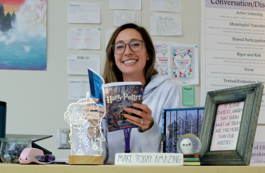 Literary and language arts teacher Kate Avery is all smiles as she makes it to her favorite part of “Harry Potter & the Sorcerers Stone” during one of her annual re-reads. Accompanying her on her desk is an assorted set of Harry Potter-related items: a snow globe of a snowy owl resembling Harry’s pet owl Hedwig, a framed photo of Avery’s favorite quote from the Harry Potter series and a lamp depicting various symbols featured prominently in the novels. While Avery no longer buys licensed ‘Harry Potter’ merchandise, she enjoys having more subtle nods to the series adorning her classroom.