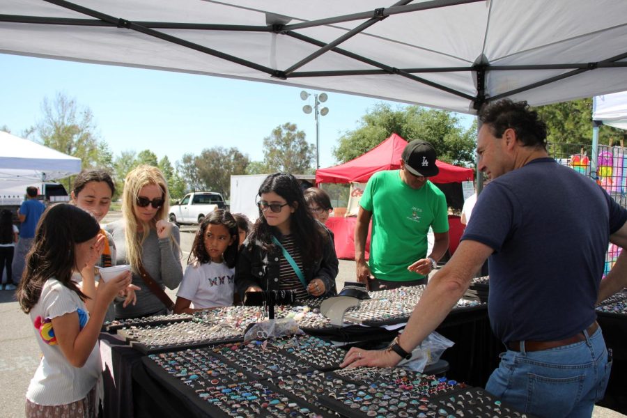 Simon Hilton, owner of Simon International at Orange County Great Park Farmers Market, talks to customers about his various designs and styles of rings on March 27. The farmers market features items like jewelry and clothes in addition to food items. 