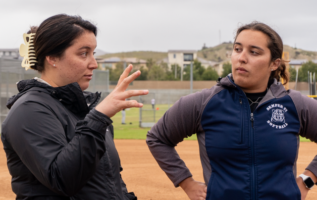 Assistant softball coach Jamie Gilbert and head softball coach Chloe Gilbert discuss the girls’ softball team’s defense as the team prepares to practice fielding on March 31. “Both of our coaches are very passionate about what they do,” senior Alexa Becerra said. “They’re both very strict, but they both have a very funny and charismatic personality, and it makes us all want to have more fun.”