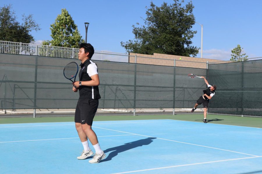 In their second match, junior Chris Li prepares his footwork for volley while senior Daniel Tu makes his second flat serve.