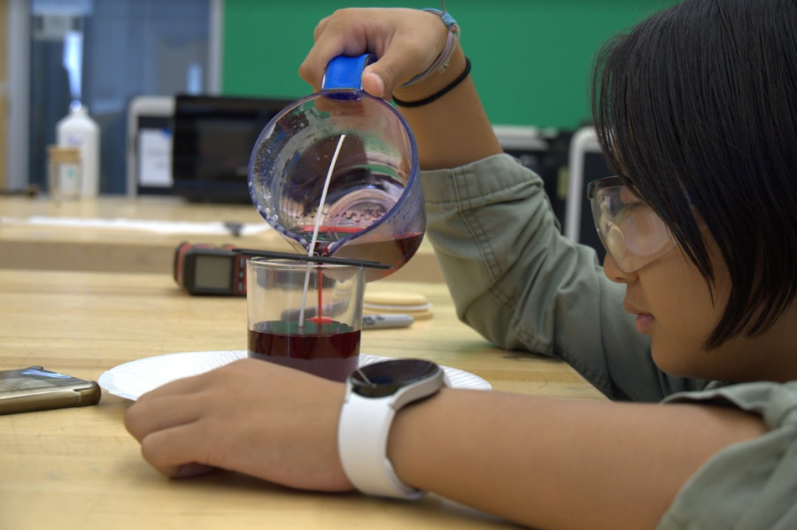 Senior Danae Dang carefully pours molten wax into a jar. Careful attention to detail – in this instance a slow, steady pour to ensure that no stray bubbles form – is necessary to achieve a satisfactory final product, according to media technician Amanda Cramer.