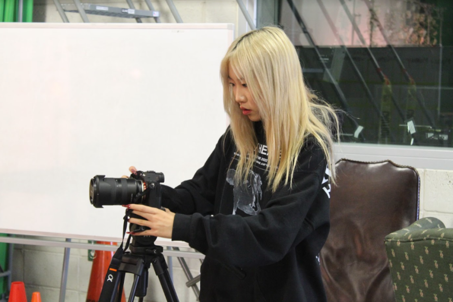 Special segment producer and senior Daisy Liao hooks up the camera to the stand for the shooting of the Belonging project in the green room. “Every single year, we can create a video like this where we get a bunch of many students into one video and ask them, ‘What does this emotion or what does the theme of this school year mean to you?’” Liao said.