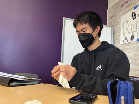 Sophomore Viget Vuong folds craft paper to create part of his origami magic ball. For origami beginners, Vuong recommends reading origami books with instructions or watching videos online. 