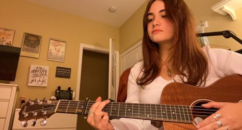 Junior Liz De Maria practices playing her acoustic guitar at home after school. De Maria first began her journey with the ukulele, learning her first song, “Riptide” by Vance Joy, in under four days, according to De Maria.