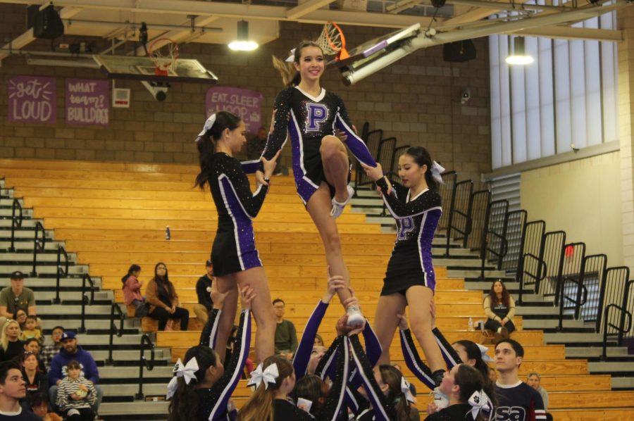 Freshman and flyer Rhys Riordan soars to the top of the pyramid stunt, supported by her fellow bases and flyers.