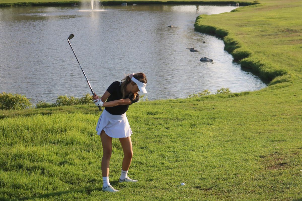 Co-captain and senior Michelle Moon extends her driver backwards in order to achieve optimal yardage on her swing at hole six.