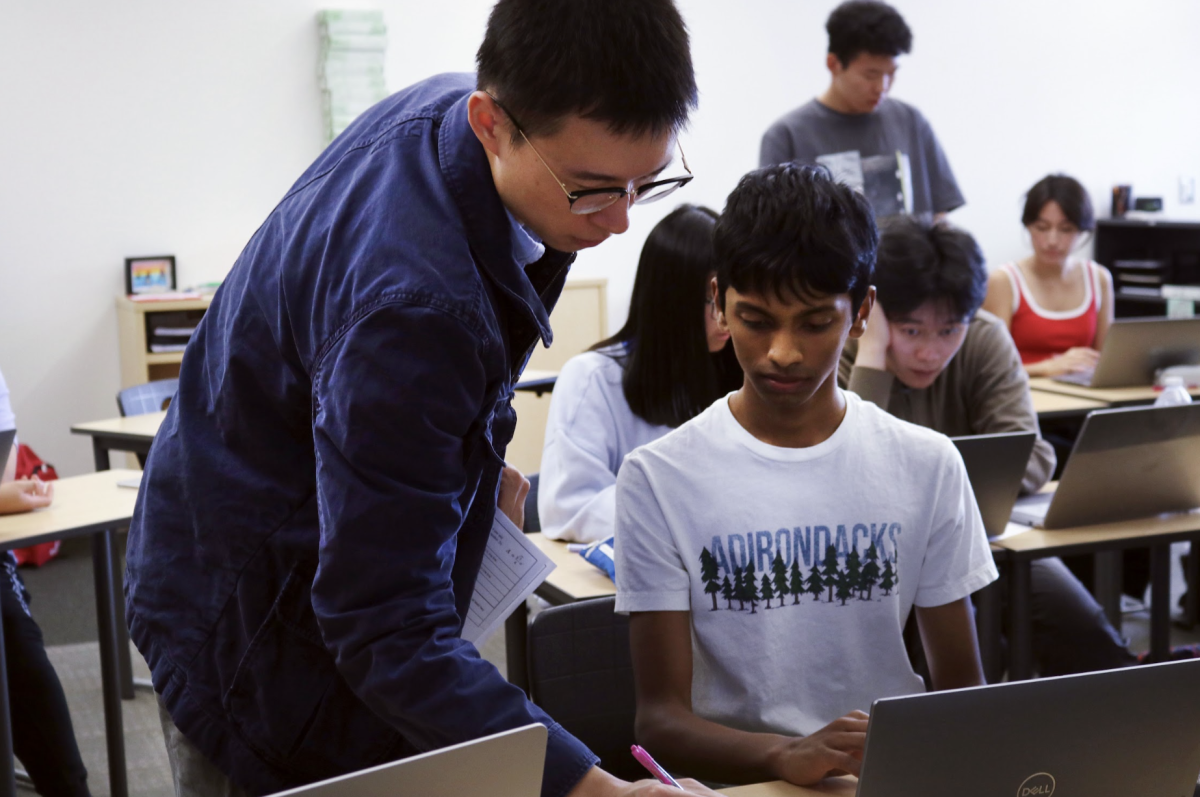 Math and computer science teacher Ran Gu debugs code alongside senior Vishak Iyer, who just began learning the computer programming language Python. Gu said his move to Portola was driven by his love for teaching computer science, as funding a computer science course is difficult at a middle school.