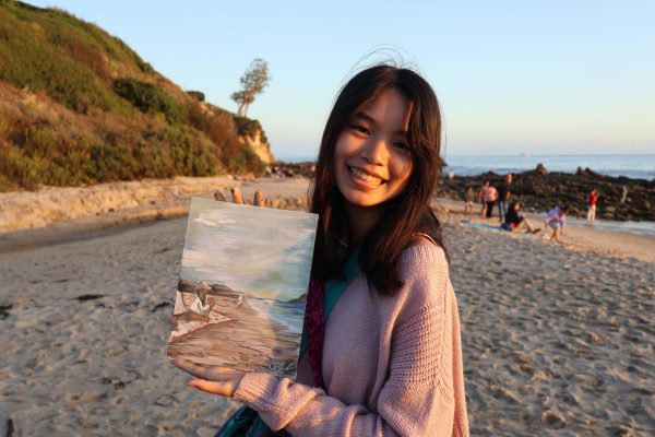 Sophomore Cara Lin holds up one of her artworks next to the scene she painted. An experienced plein-air painter, Lin enjoyed meeting with friends and seeing her art improve from last year. “I’m proud of my art having changed,” Lin said. “It’s good that it’s different; I don’t want it to stay the same.”