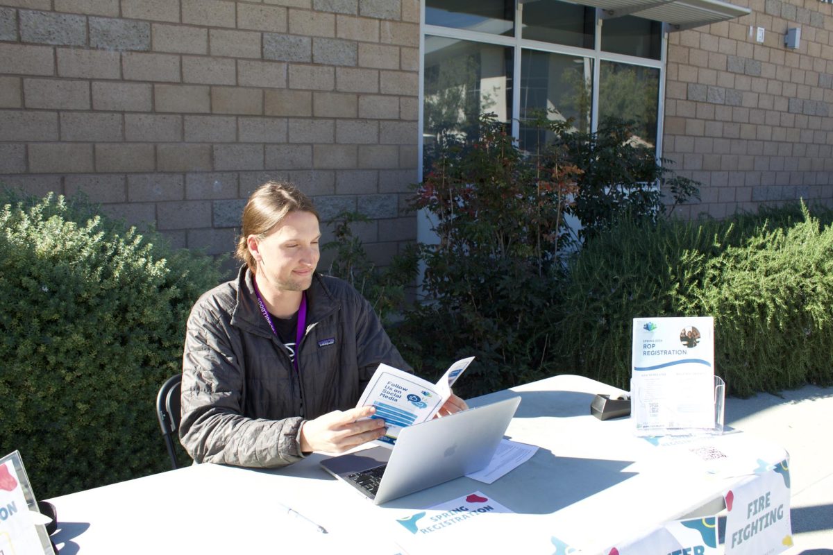 ROP Career Specialist Gage Peterson sits at a table that the counseling office set up during lunch on Jan. 12 to give students information about Coastline ROP. Peterson said ROP courses are great opportunities for all kinds of students, from those who have a specific trade or vocation in mind for their futures to those who want to explore new fields and interests or prepare for a preferred subject of study at a four-year university. Opportunities to interact with students and staff like this are what have shaped Peterson’s experiences at Portola High so far. “Its just been a great, great place to learn and train and see how to best serve students — by learning from the counselors that are here and then also the students,” Peterson said.