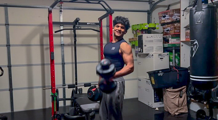Senior Haaris Alam completes single-arm dumbbell bicep curls at his home gym. Alam says that he finds weightlifting to be relaxing and considers it to be one of his favorite hobbies.