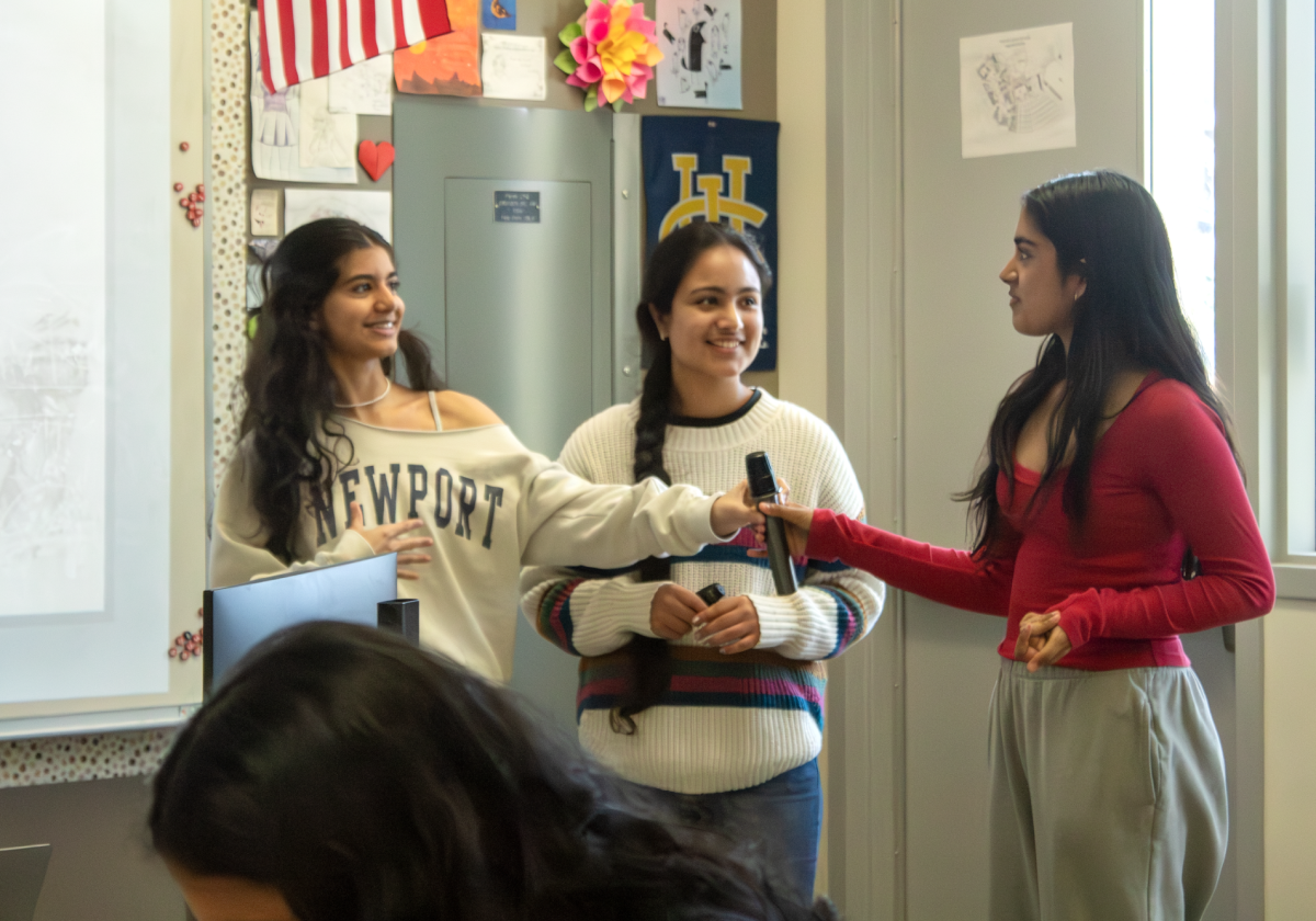 Girls Who Code (GWO) co-President and senior Injila Adil hands a microphone over to Planet Protectors President and junior Sahana Ananth during their meeting on March 20. The two clubs plan on collaborating to code an app designed by Planet Protectors that promotes environmental consciousness, according to GWO co-President and sophomore Avnit Kaur.