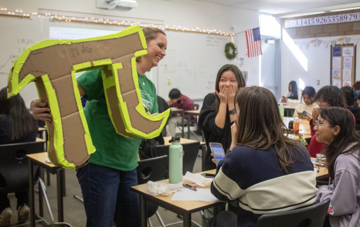 Clarke smiles with some of her Math 1 students during their Pi Day festivities, which began after a quiz, allowing them to unwind and have fun at the end of the day, according to freshman Peter Cooke. Clarke said many students pitched in by bringing food and drinks for the party, and Cooke even made her the pi model.
