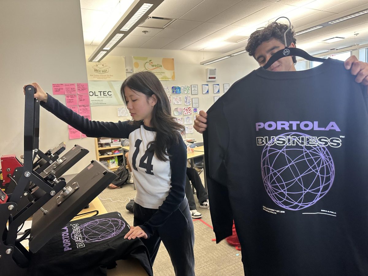 Senior Yunxin Tao and sophomore Aditya Nair manufacture t-shirts for Portola Printing, Portola Highs first ever business. “Sometimes after school, we have a little party with about five to 10 students, heat pressing and folding and quality checking,” business teacher Katherine Dillon. “The next day, we count the orders and make sure we have all the right sizes, all the right numbers [to] make sure theyre all good and then we just go deliver it to the classrooms.”