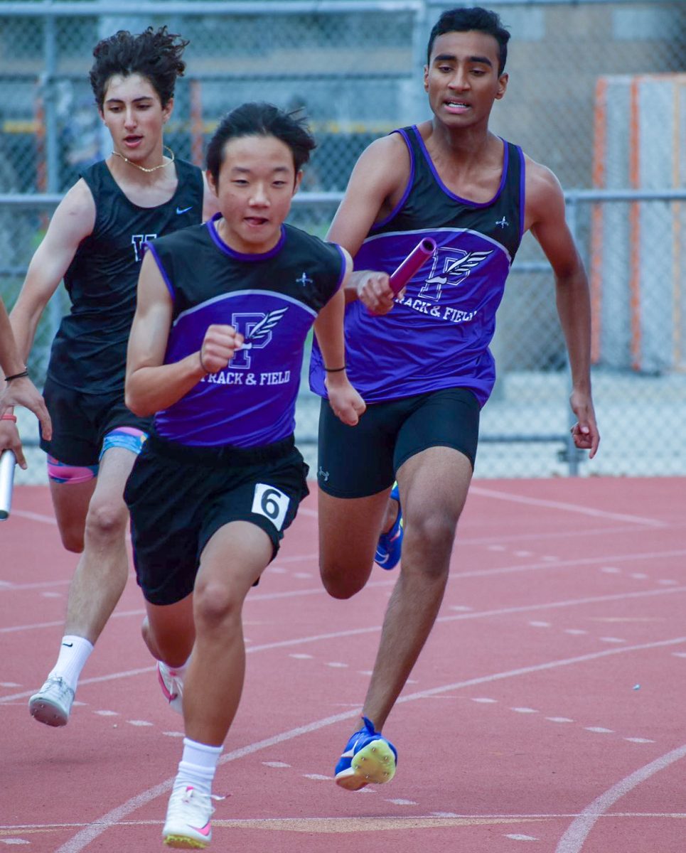  JV track captain and senior Amogh Baddam works with his teammate, sophomore Hyoora Lee, during the 4x100 relay to ensure a successful baton pass. “Chemistry is a really overlooked part of a relay,” Baddam said. “You have to be able to anticipate how your partner is going to react to something not going right in a race and what to do if your baton exchange isn’t perfect, which it won’t always be. And I think that’s a huge part of having success as a team because there’s only so much you can do on your own.”