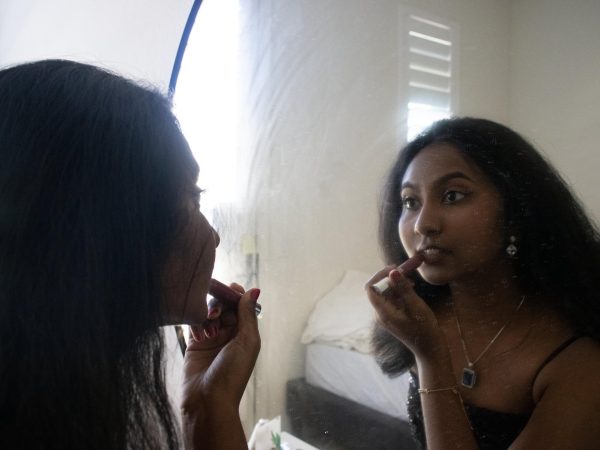 To add the final component of her look for prom, senior Rithu Madhyanam carefully applies lipstick while looking in the mirror.
