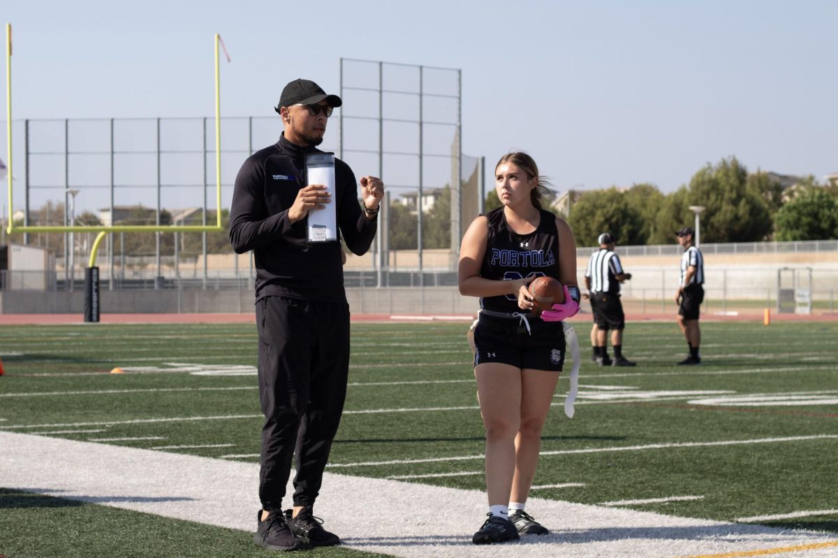 Quarterback and sophomore Alondra Hernandez speaks with coach Desmond Hamilton during halftime about her throwing technique. According to head coach Julie Primero, the team has been working towards refining their strategies for the game.