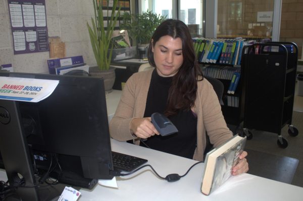 Librarian Phoebe Kern scans a book and checks it out for a student. “I consider my most important role as a librarian to create free and equitable access to information and to foster a safe and inspirational space for students [to] interact with that information in an encouraging learning environment,” Kern said.
