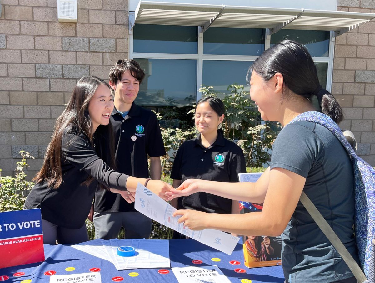 YAT leader, Youth Outreach Program member and junior Chloe Chen hands a registration form to senior Morgan Tien during the voter registration drive on Oct. 10. “It's important that all levels of our government and our community [are accessible] to more people because we see today [there are] some restrictions in different areas of the country and people being more dissatisfied with the government,” YAT leader, Youth Outreach member and senior Aaron Owens said. “We want people to have a chance to connect with their government, to actually make a change that they want to see.”
