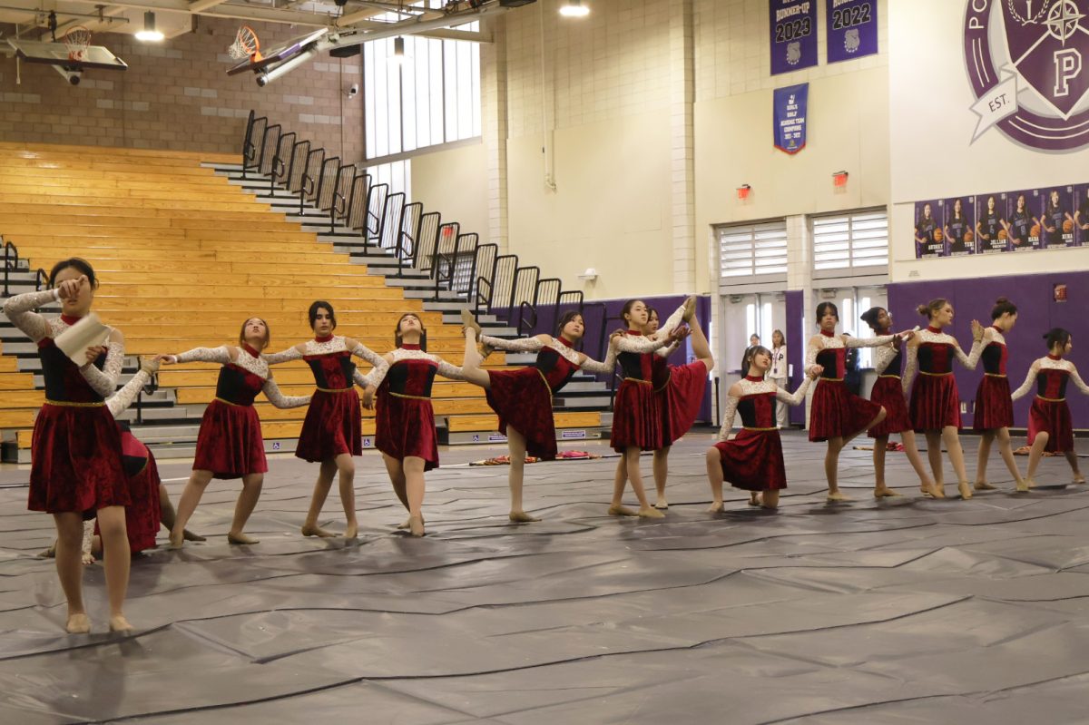 Winter guard opens their show ‘Burn’ by passing a scroll through a line of dancers. Before beginning their performance, the team stands in a circle to motivate one another, according to color guard member and senior Leah Sim.