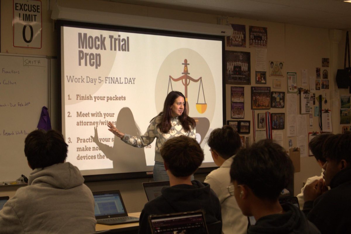 History teacher Megan Saia answers a question from a student about the mock trial for Honors American History, helping them understand the requirements for the project. Her guidance has helped many students improve important skills like public speaking. 