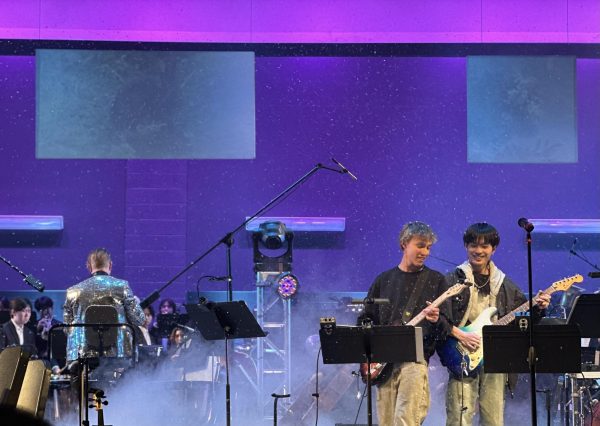 Lead guitarist and junior Ethan Williams and rhythm guitarist and senior Eddie Chen rock the stage in a rendition of the Tran-Siberian Orchestra piece “First Snow,” which  is conducted by instrumental music director Desmond Stevens. “Being able to have the rock musicians on stage with the orchestra musicians and having the full wind band on with everyone else puts nearly 100 students on stage together,” Stevens said. “Then [having] that element of all the lighting and effects and the students in the control room running that at the same time really builds [a] larger community.”