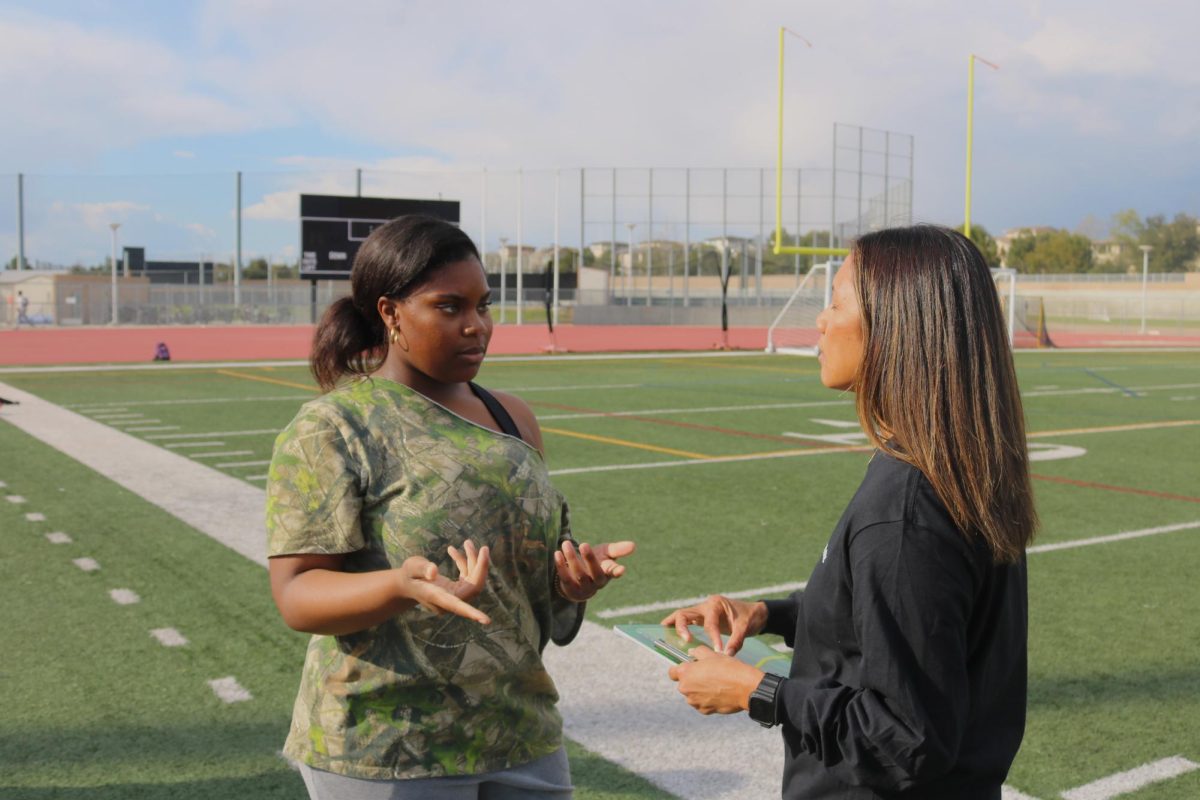 Senior Sanaa Bullock talks strategy on the field with Flag Football coach Julie Primero. Bullock helps the team run more efficiently and keeps spirits up, according to Primero. “[She takes] care of things so that we [can] really focus on practice, getting better, prepping for games, stuff like that,” Primero said. “If they see something that needs to be taken care of, they do it without asking me so that I can focus on coaching. I think it carries over to being an organized leader.”