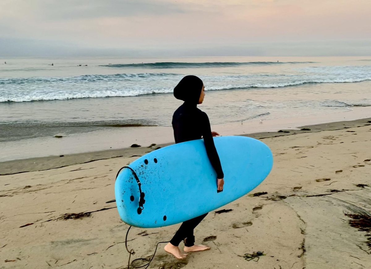 Senior Shifa Harsolia walks along the beach with her surfboard during a PHS Surf and Snow Club meetup. “There's definitely a learning curve for surfing and getting over that hump is when you really enjoy it,” Harsolia said. “And it's hard at first, but if you just stay mentally present and keep going, it becomes much more rewarding.”