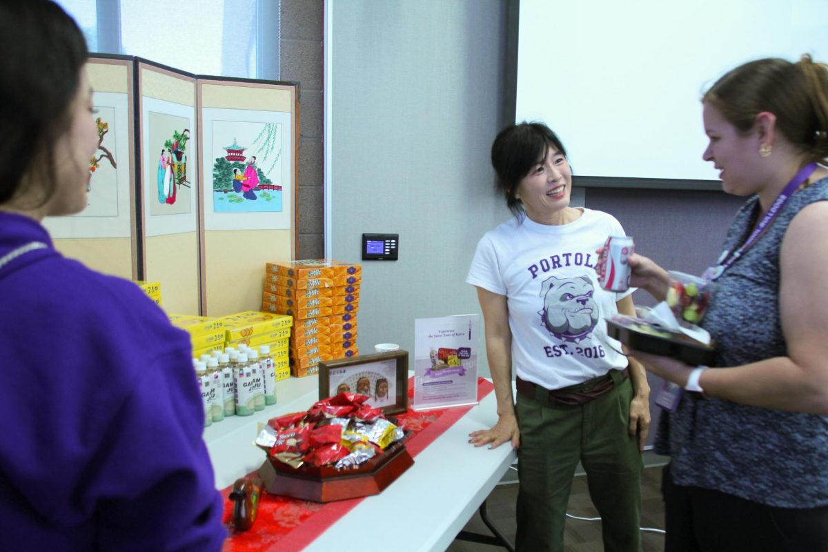 Irvine Korean Parent Association member Hyojin Kwon stands by the snack table and hands out Korean snacks and drinks to science teacher Meghan Truax. “They had a ton of food,” Assistant Principal Brandon Emery said. “They had a really good selection like, beef, vegetarian, spicy, which was really nice and considerate to different people's dietary needs. They had videos playing in the background of K-pop. It was really interesting to have that. And it was really well attended. People seemed really happy with it.”
