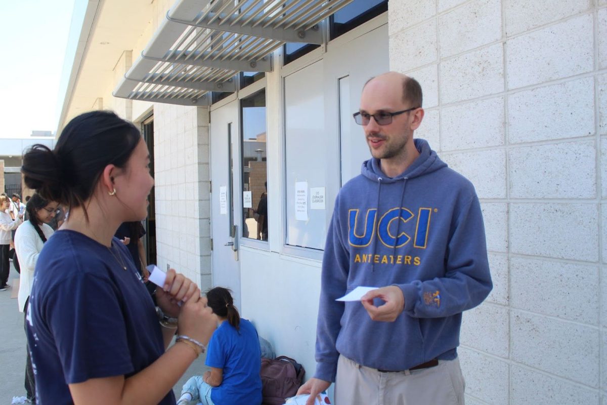 Physics teacher Ryan Johnson speaks to junior Chloe Chen about the AP Physics and Engineering boat project outside the engineering classroom. In his new classes, Digital Electronics and Honors Engineering Design and Development, Johnson is excited for more hands-on projects. “We'll be able to create products that are directly relevant to society's needs, as opposed to practicing doing something which is what most high schoolers are doing,” Johnson said.