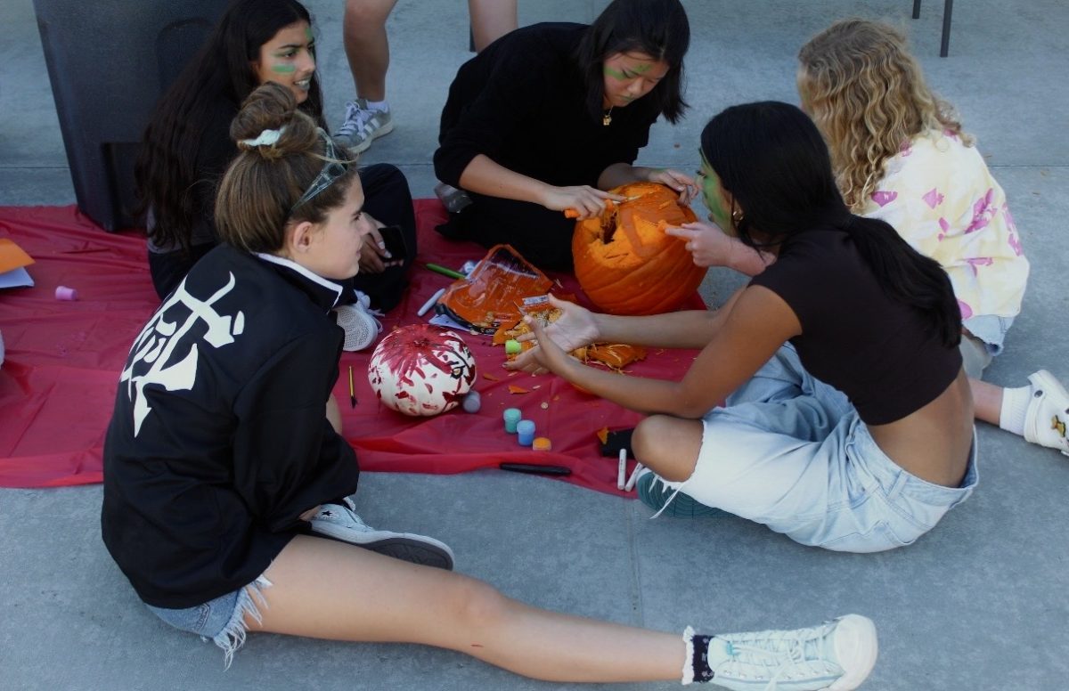 Members of Girls water polo work together on a pumpkin carving activity during their annual Halloween practice, combining team bonding with seasonal fun. “The teams are made up of a mix of varsity and [junior varsity] players, so you learn to work with each other regardless of skill level,” varsity captain and senior Alexis Minasyan said. “Because you’re relying on each other more, you end up knowing each other better and working better together in the water during games.”